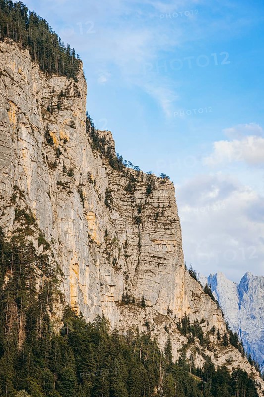 Steep rock face with forest at its feet, rising into blue sky, Admont, Styria, Austria
