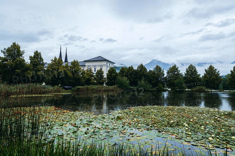 Admont Abbey behind a pond surrounded by trees, Admont, Styria, Austria
