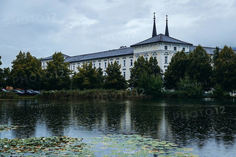 Admont Abbey is reflected in a pond surrounded by trees, Admont, Styria, Austria