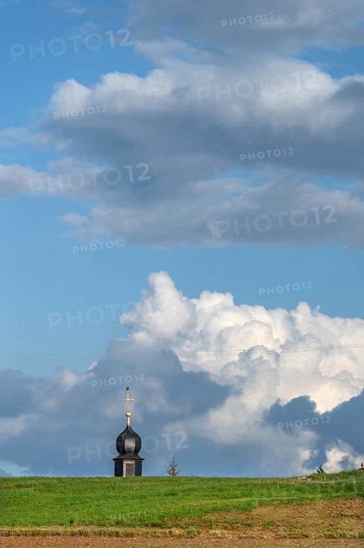 Tower of a chapel behind a meadow hill, cloudy sky, Köttweinsdorf, Upper Franconia, Bavaria, Germany