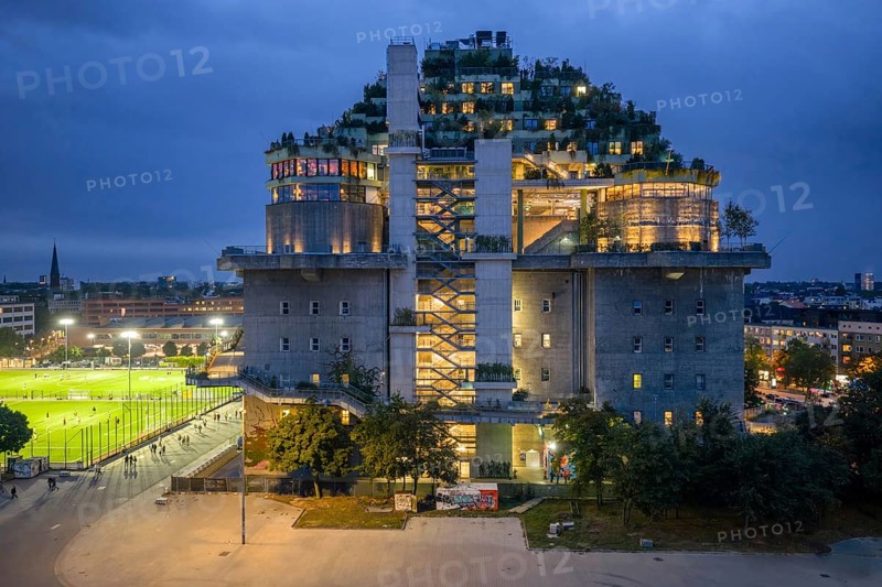 Aerial view of the Hamburg bunker on Heiligengeistfeld during the blue hour with illuminated floors and green trees at night, Hamburg, Germany