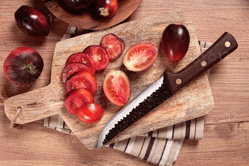 Sliced tomatoes, Black Beauty variety, on a cutting board, top view, on the kitchen table