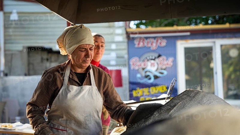 A Turkish woman bakes traditional bread on a clay tandoor oven in a rural village, Hatay, Hatay, Türkiye