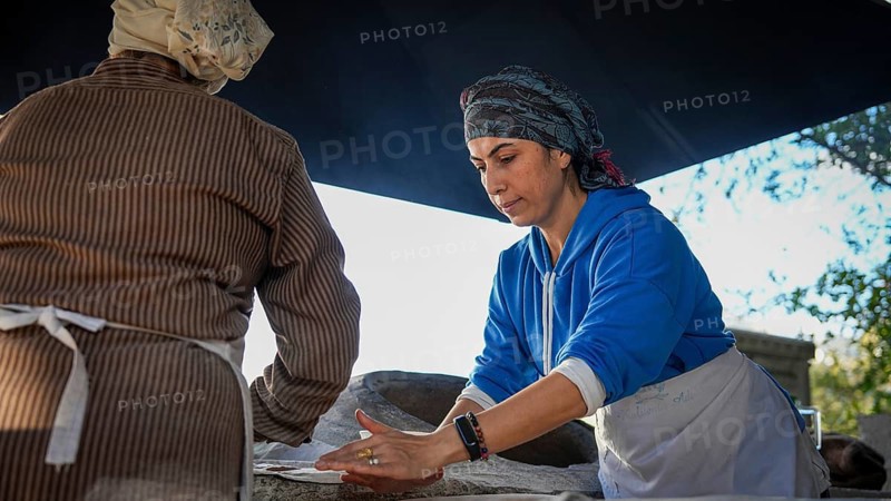 A Turkish woman bakes traditional bread on a clay tandoor oven in a rural village, Hatay, Hatay, Türkiye