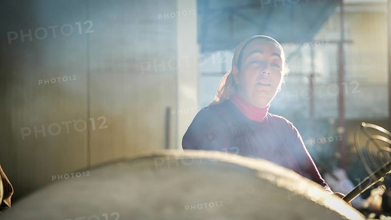 A Turkish woman bakes traditional bread on a clay tandoor oven in a rural village, Hatay, Hatay, Türkiye