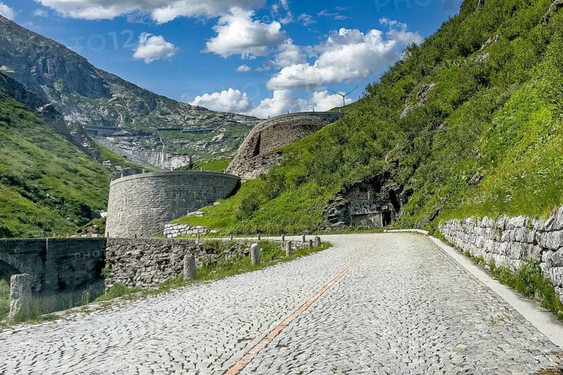 Part of southern ascent of south ramp of historic Gotthard pass road Tremola with cobblestones, in the background retaining walls for serpentines narrow hairpin bends on steep mountainside, Canton Ticino Ticino, Switzerland