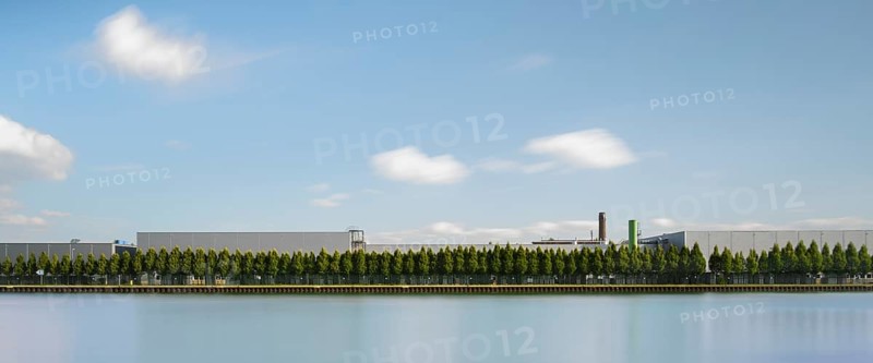 View across the Mittelland Canal to an industrial building with trees growing in front of it, long exposure, Garbsen, Hanover, Lower Saxony, Germany