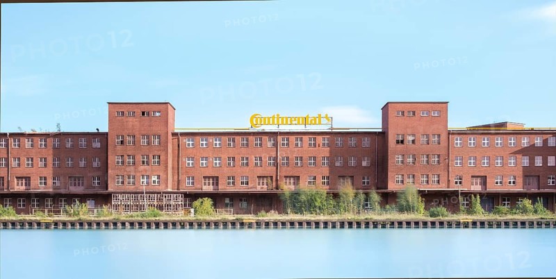 View across the Mittelland Canal to an industrial building with trees growing in front of it, long exposure, Garbsen, Hanover, Lower Saxony, Germany