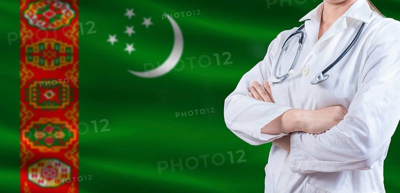 Doctor with crossed arms on Turkmenistan flag. Turkmen health and care concept. Female doctor on Turkmenistan flag