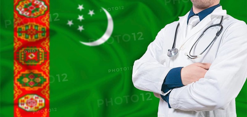 Turkmenistan healthcare concept. Male doctor on Turkmenistan flag. Doctor with crossed arms on Turkmenistan flag