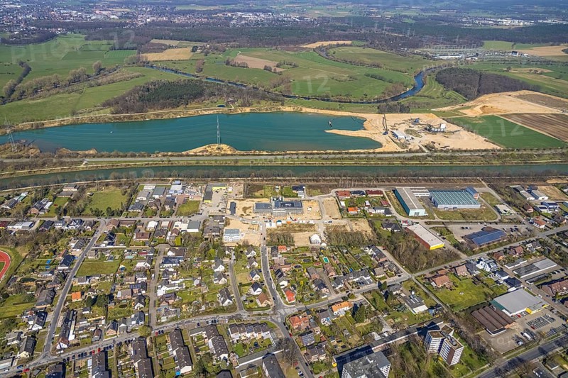 Aerial view, construction site and new building in the industrial estate Friedrichsfeld, Poststraße, Wesel-Datteln-Kanal, RMKS RHEIN MAIN KIES UND SPLITT with lake, river Lippe with Lippe floodplain, Friedrichsfeld, Voerde, Ruhr area, Lower Rhine, North Rhine-Westphalia, Germany, construction work, construction area, construction site, building plots, construction, construction project, construction site, DE, Europe, commercial enterprises, commercial area, commercial area, commercial site, commercial use, industrial area, industrial site, aerial view, aerial photography, aerial photography, new construction, overview, bird's-eye view, overview