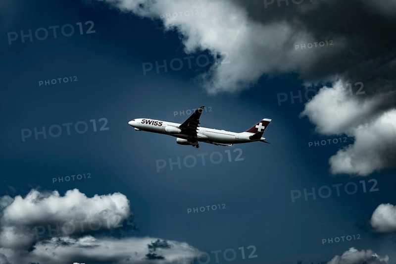 Swiss Airlines Passenger Airplane Flying Against Blue Sky and Clouds in a Sunny Summer Day From the Airport in Kloten, Zurich, Switzerland