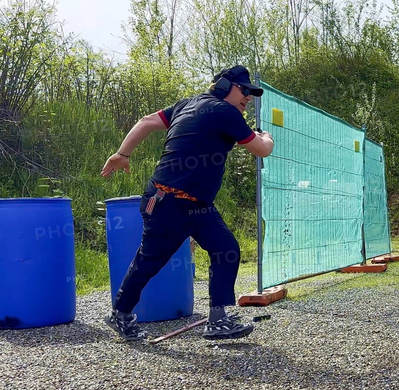 Man with Cap and Protection Eyeglasses Running and Holding a Handgun Backward in IPSC Shooting Sport in Switzerland
