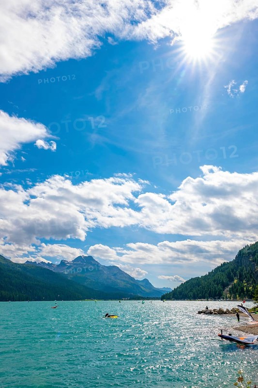 Windsurfing and Wingsurfing on Alpine Lake Silvaplana in a Sunny Summer Day with Mountain View in the Swiss Alps and Sunbeam in Silvaplana, Maloja, Grisons, Switzerland