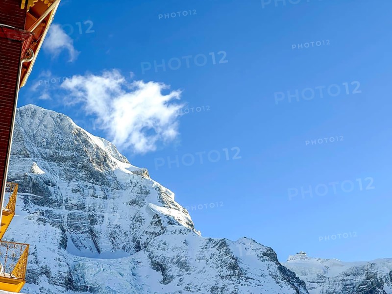 Hotel and Snowcapped Mountain Peak Mönch at 4107 Meter High in the Swiss Alps in a Sunny Winter Day with Blue Sky in Grindelwald, Bern Canton, Switzerland