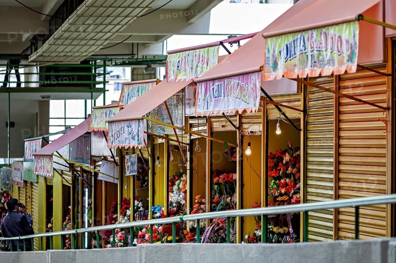 Quiet row of flower shops with creatively presented, colourful flowers, small shops and restaurants in the market halls of La Paz in Bolivia