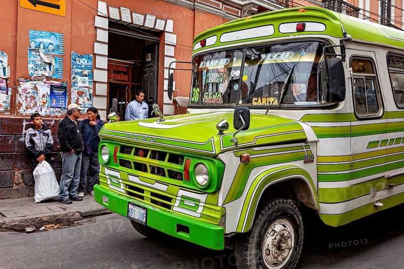 Green retro bus in front of a municipal building with people on the pavement, The colourful buses of La Paz in Bolivia
