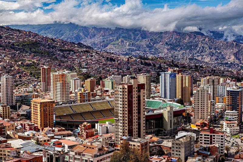 Panorama of La Paz with a view of skyscrapers and a stadium against a mountain backdrop, The houses and skyscrapers of the city centre of La Paz in Bolivia