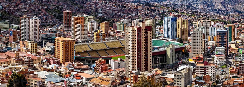 Urban scenery with stadium and skyscrapers in front of mountains, The houses and skyscrapers of the city centre of La Paz in Bolivia