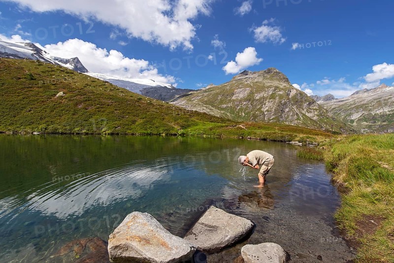 Hiker refreshes himself in the Salzbodensee lake on the glacier show trail in the Tauerntal valley, Hohe Tauern National Park, East Tyrol, Austria