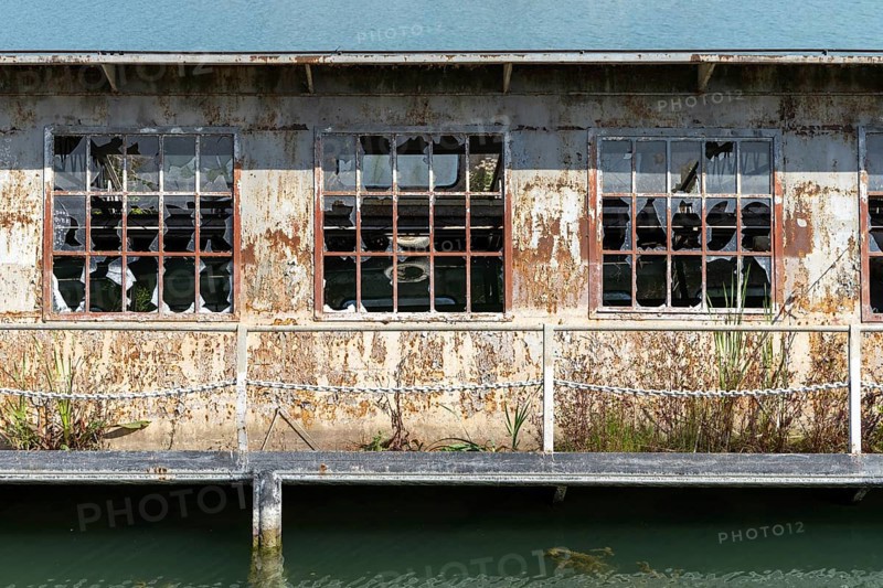 Abandoned building with broken windows and rust next to a body of water, at the harbour of Linz Upper Austria Austria