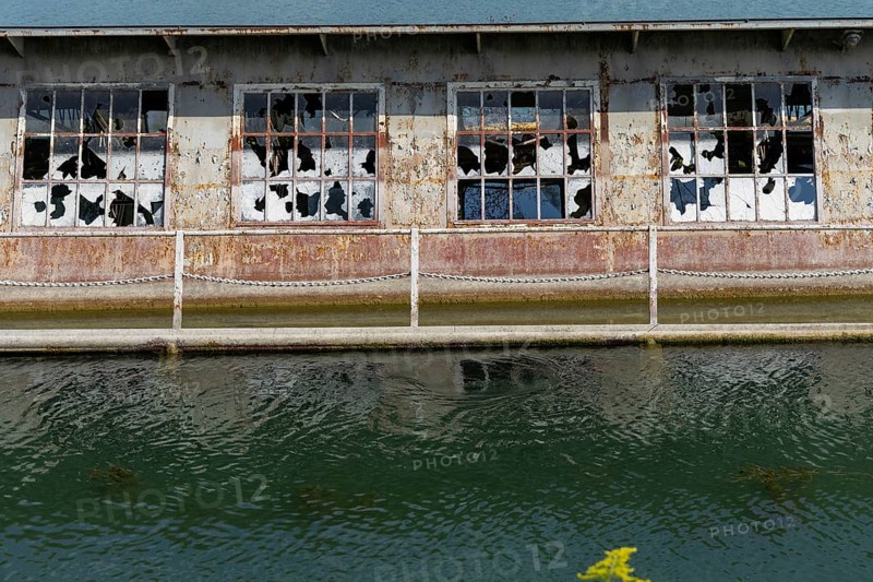 Dilapidated building with broken windows and rusty structures on the waterfront, at Linz harbour Upper Austria Austria