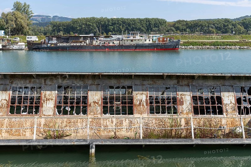 Dilapidated industrial building with destroyed windows directly on the waterfront, at the harbour Linz Upper Austria Austria