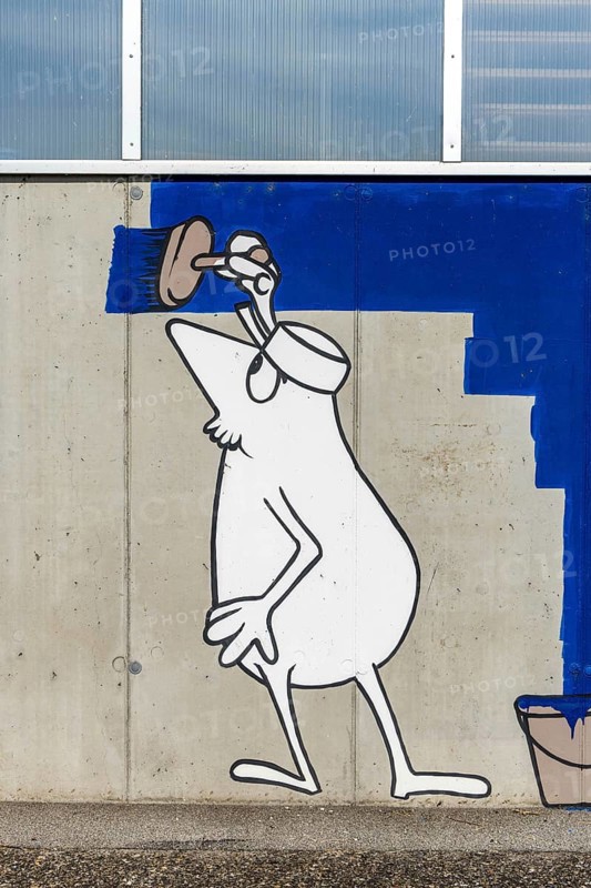 Cartoon painter painting an abstract blue surface on a concrete wall at the harbour of Linz Upper Austria Austria