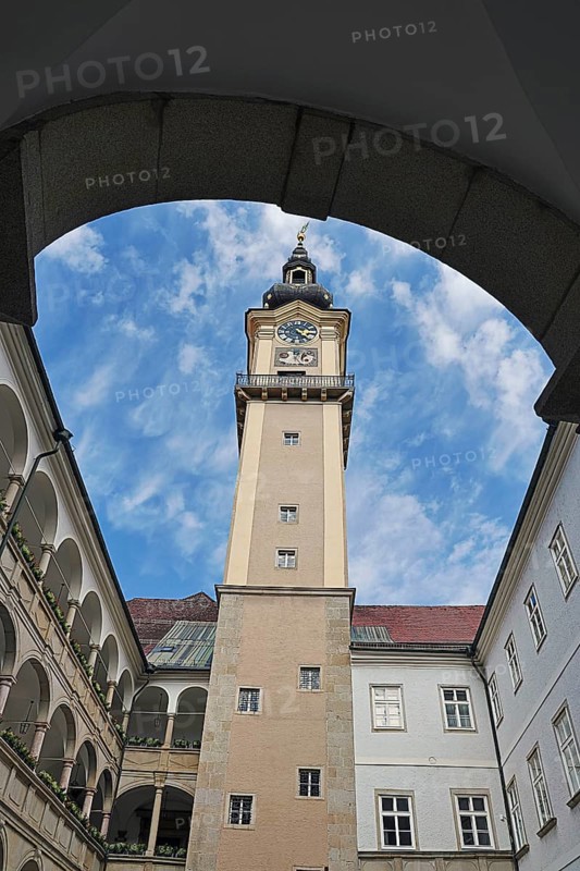 View through an arch onto a historic clock tower with blue sky, Arkardenhof Landhaus Linz Upper Austria Austria