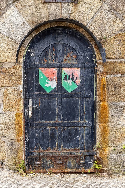 Old door with coat of arms on a stone wall, surrounded by rust and weathering, Pöstlingsbergkirche pilgrimage basilica Sieben Schmerzen Maria Linz Upper Austria Austria