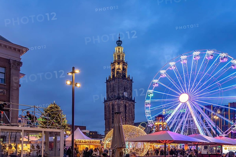 Ferris wheel on the Grote Markt at Christmas time and the Martinitoren or Martini tower of the Martinikerk or Martini church at dusk, Groningen, Netherlands