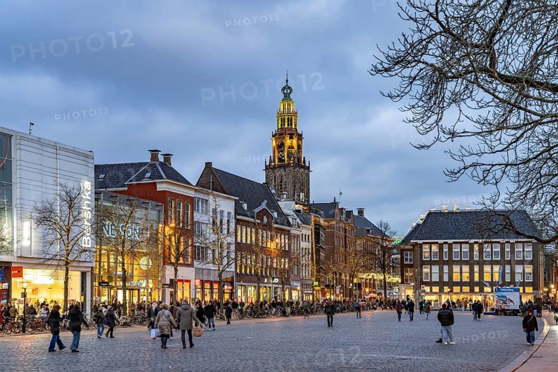 Shops at the fish market Vismarkt and the church tower Martinitoren or Martinitower of the Martinikerk or Martinikirche at dusk, Groningen, Netherlands