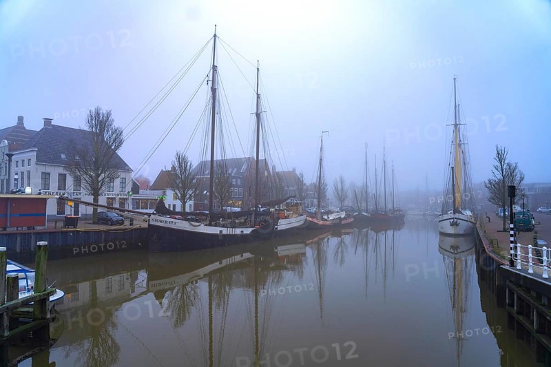 Typical canal with sailing boats in the winter fog, Harlingen, Friesland, Netherlands