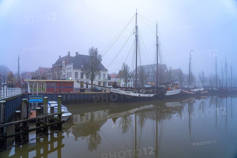 Typical canal with sailing boats in the winter fog, Harlingen, Friesland, Netherlands