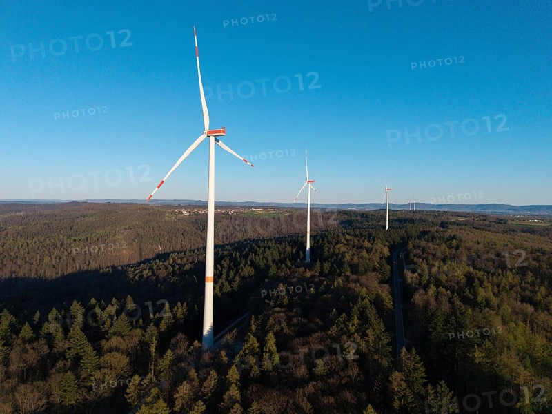 Wind turbines rise above the forest under a cloudless blue sky, near Schorndorf im Remstal, Baden-Württemberg, Germany
