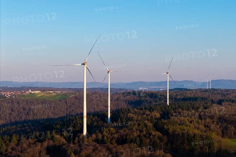Several wind turbines stretch across a wooded landscape under a clear sky, near Schorndorf in the Rems Valley, Baden-Württemberg, Germany