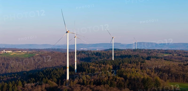 Wind turbines stand on a forest landscape with a clear blue sky in the background, near Schorndorf in the Rems Valley, Baden-Württemberg, Germany