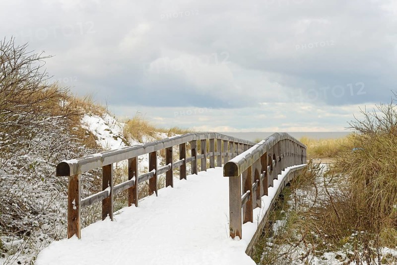 Winter day, onset of winter, wooden plank path leads through the snow-covered dune landscape to the North Sea, Norddeich, Lower Saxony, Germany