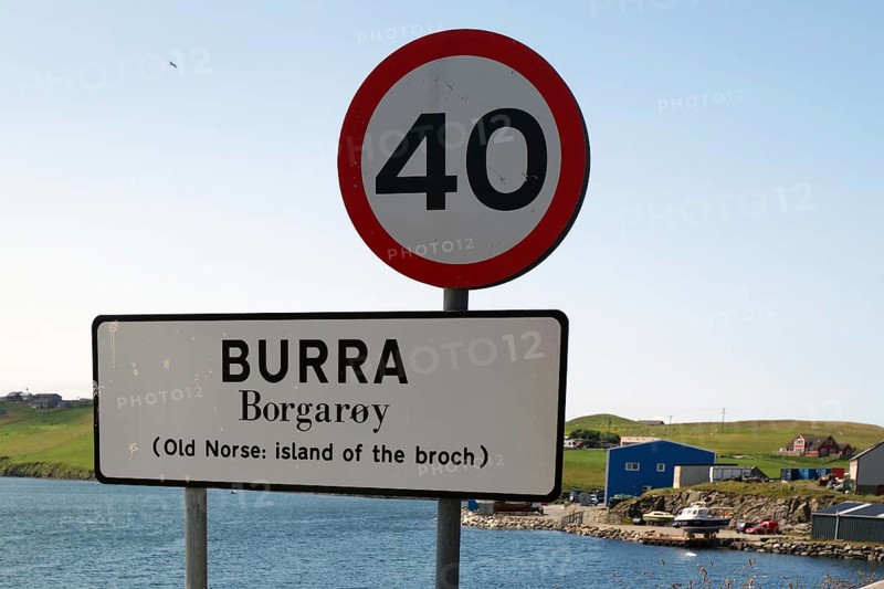 A road sign on an island with a clear blue sky and a body of water in the background, reference to the old Norwegian spelling, Shetland Islands, Scotland, Great Britain