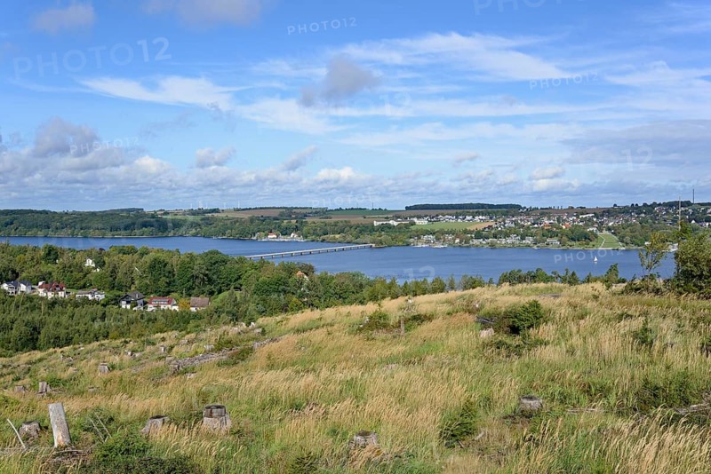 View over the Möhnesee, Körbecke village with the lake park and the lakeside promenade, blue cloudy sky, Möhnetalsperre, North Rhine-Westphalia, Germany