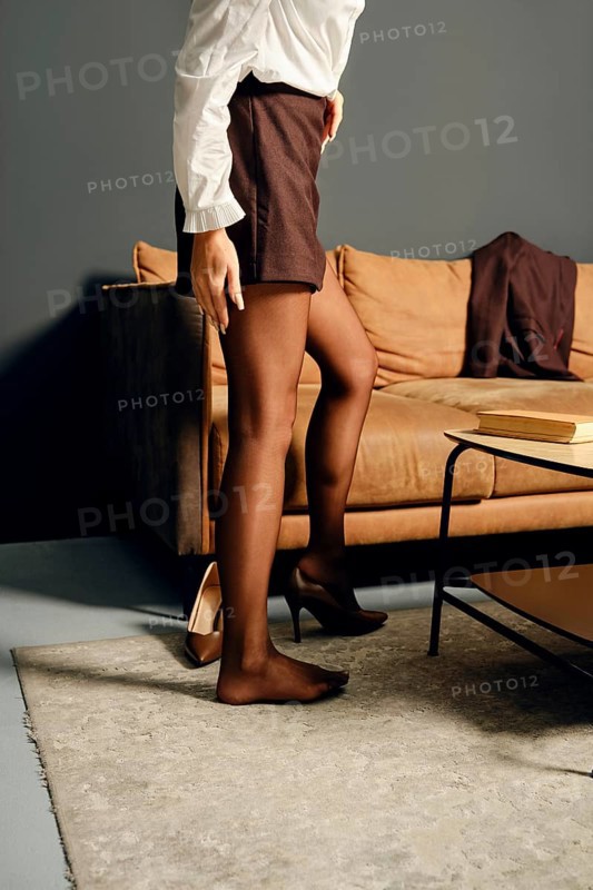 Unrecognizable woman put on high heels in a modern living room