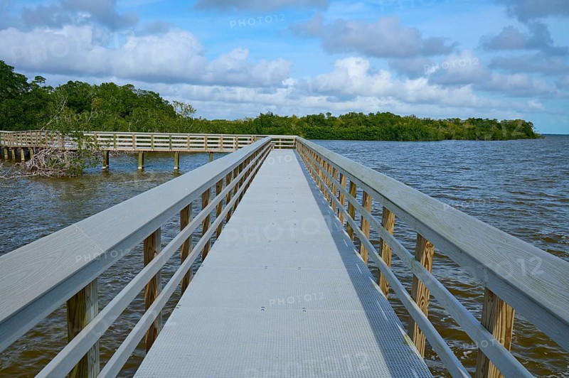 A long wooden walkway leads into the water, under a cloudy sky, West Lake View Point, Everglades National Park, Florida, USA
