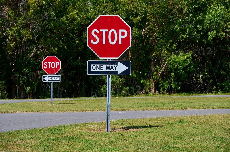 Stop signs and one-way street signs in front of a green tree landscape, Flamingo, Everglades National Park, Florida, USA