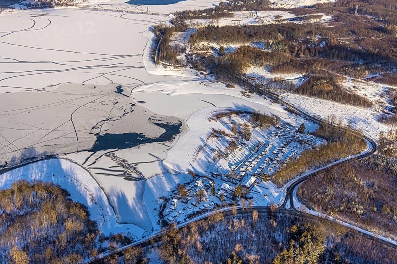 Aerial view, snow-covered campsite Möhnesee, forest area and Möhnesee, Brüningsen, Möhnesee, Sauerland, North Rhine-Westphalia, Germany, mountains and valleys, camping, camping site, camping houses, campsite, DE, Europe, distant view, leisure, hilly landscape, aerial view, aerial photography, aerial photography, cracks in the ice, snow, south shore, overview, bird's eye view, winter at Möhnesee, winter landscape, caravan, birds-eyes view, overview
