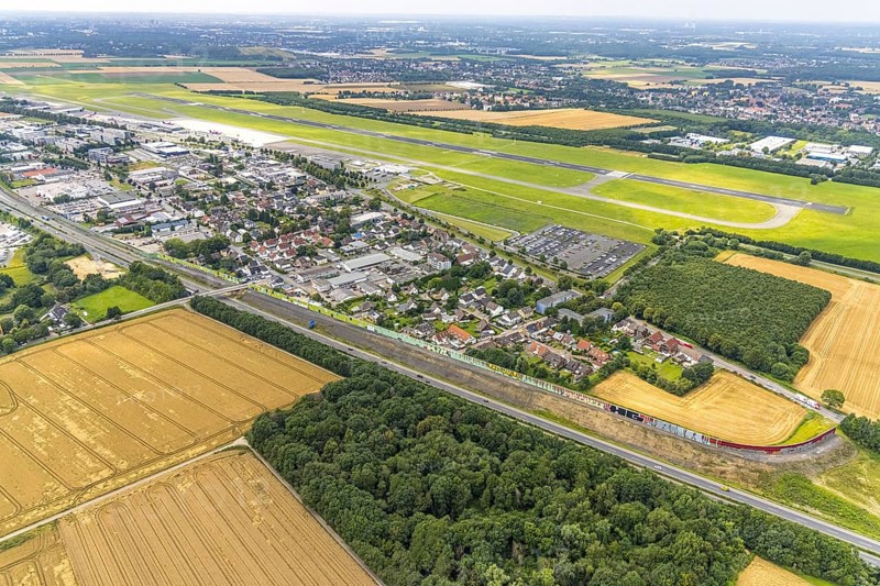 Aerial view, Dortmund Airport, residential area and commercial area Chaussee with noise protection wall on the B1 federal road, Obermassener Heide, Holzwickede, Ruhr area, North Rhine-Westphalia, Germany, DE, Europe, flight emission, airport, aircraft noise, airfield, commercial enterprises, commercial area, commercial area, commercial location, commercial use, property tax, real estate, industrial area, runway, aerial view, aerial photography, aerial photography, runway, overview, bird's-eye view, residential area, residential area, residential buildings, residential quality, residential neighbourhood, housing estate, birds-eyes view, overview