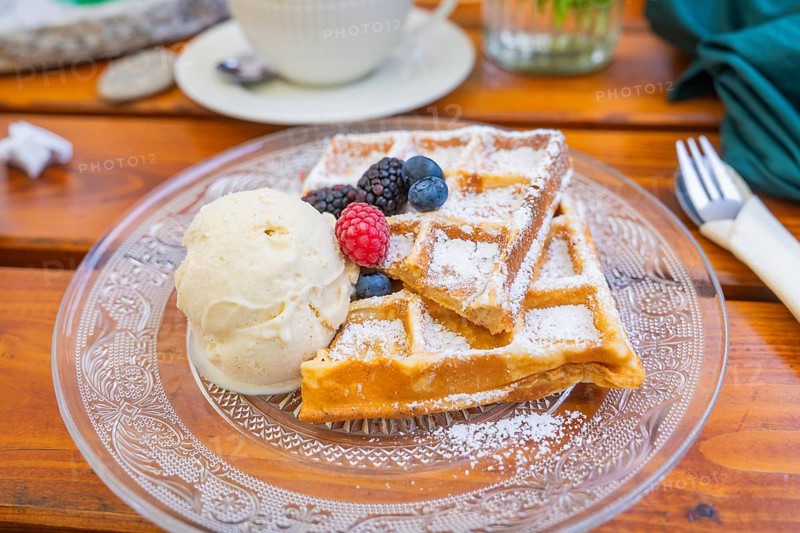 Close-up of waffles with berries and ice cream on a plate on a wooden table