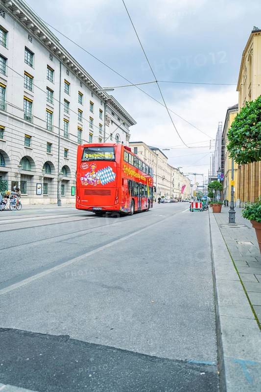 A red double-decker bus on an empty street in Munich under a cloudy sky, Munich, Germany