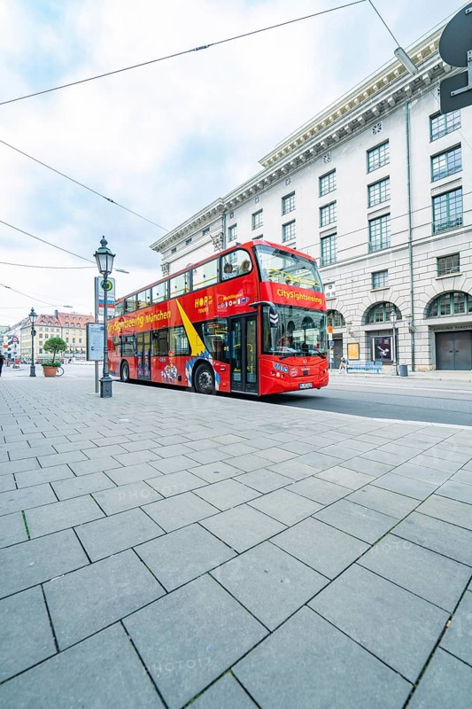 A red double-decker bus for city tours in front of historic buildings in Munich, Munich, Germany
