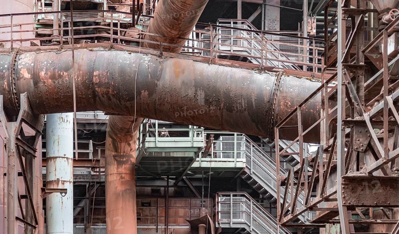 Weathered rundown industrial scenery with old corroded steel girders, stairs and metal tubes