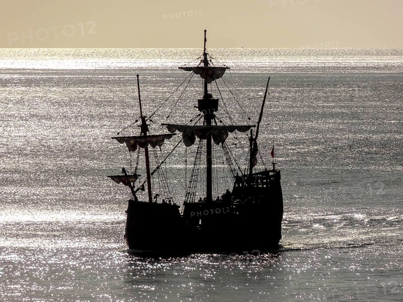 Silhouette of a historic sailing ship near Madeira in glittering water ambiance